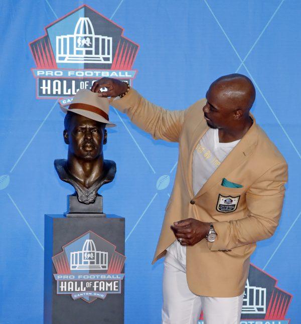 Former NFL safety Brian Dawkins poses with a bust of himself during inductions at the Pro Football Hall of Fame, Aug. 4, 2018 in Canton, Ohio. (AP Photo/Gene J. Puskar)