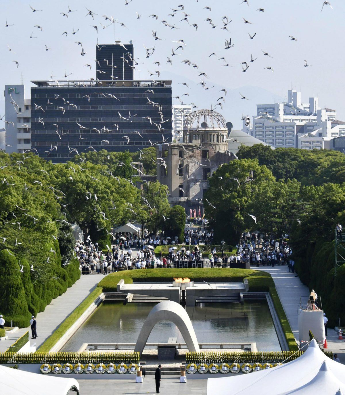 Doves fly over the cenotaph dedicated to the victims of the atomic bombing during a ceremony to mark the 73rd anniversary of the bombing at Hiroshima Peace Memorial Park in Hiroshima, western Japan, Monday, Aug. 6, 2018. The Atomic Bomb Dome is seen in center background. (Shingo Nishizume/Kyodo News via AP)