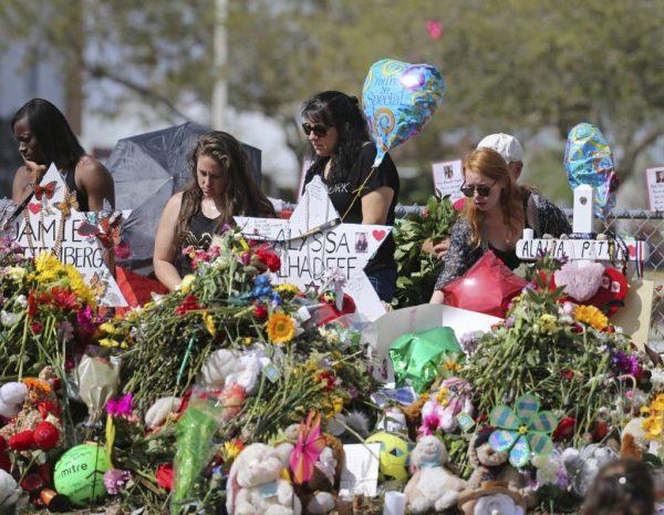 Mourners bring flowers as they pay tribute at a memorial for the victims of the shooting at Marjory Stoneman Douglas High School in Parkland, Fla., on Sunday, Feb. 25, 2018. (David Santiago/Miami Herald via AP)