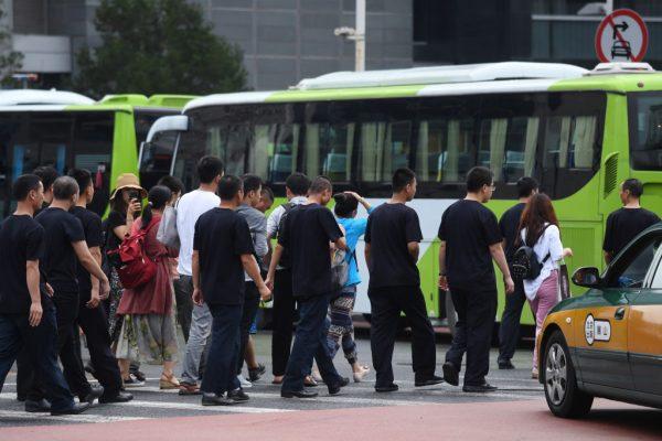 P2P petitioners are escorted to a bus by security personnel in Beijing on Aug. 6, 2018. (Greg Baker/AFP/Getty Images)