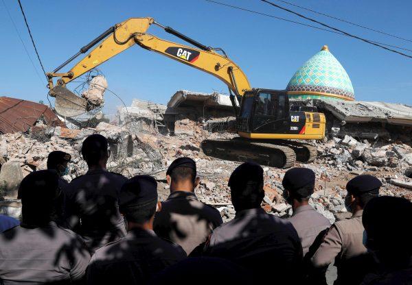 Policemen stand as heavy equipment move debris for try to find people trapped inside a mosque after an earthquake hit on Sunday in Pemenang, Lombok Island, Indonesia, Aug. 8, 2018. (Reuters/Beawiharta)