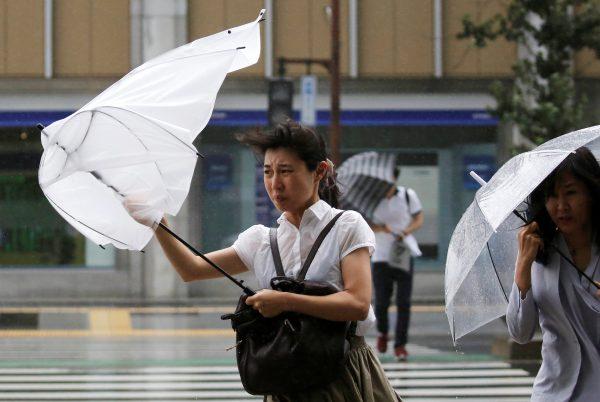 Passersby using umbrellas struggle against a heavy rain and wind as Typhoon Shanshan approaches Japan's mainland in Tokyo, Japan Aug. 8, 2018. (Reuters/Toru Hanai)