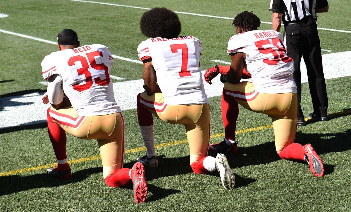 (L-R) Free safety Eric Reid #35, quarterback Colin Kaepernick #7 and outside linebacker Eli Harold #58 of the San Francisco 49ers kneel on the sidelines during the national anthem before the game against the Seattle Seahawks at CenturyLink Field in Seattle, Washington State, on Sept. 25, 2016. (Steve Dykes/Getty Images)