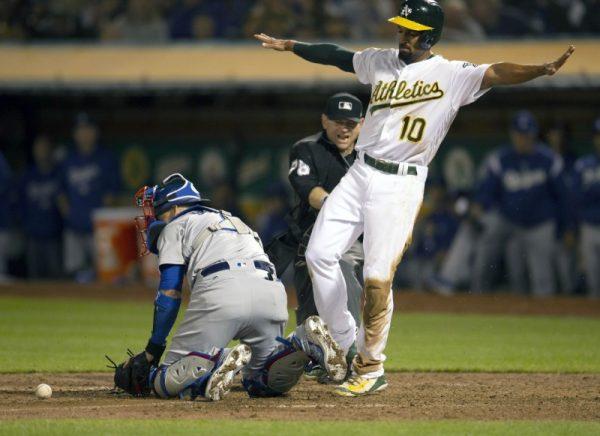 Aug. 8, 2018; Oakland, CA; Oakland Athletics shortstop Marcus Semien signals safe after sliding home ahead of the relay to Los Angeles Dodgers catcher Yasmani Grandal (left) during the eighth inning. (D. Ross Cameron—USA TODAY Sports)