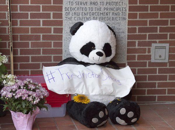 A stuffed bear forms part of a makeshift tribute outside the police station in Fredericton on Aug. 11, 2018. (Andrew Vaughan/The Canadian Press via AP)