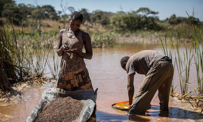 A woman and a man separate cobalt from mud and rocks near a mine between Lubumbashi and Kolwezi, Democratic Republic of the Congo, in 2015. (Federico Scoppa/AFP/Getty Images)