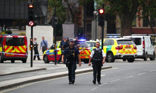 Armed police stand in the street after a car crashed outside the Houses of Parliament in Westminster, London on Aug. 14, 2018. (Reuters/Hannah McKay)