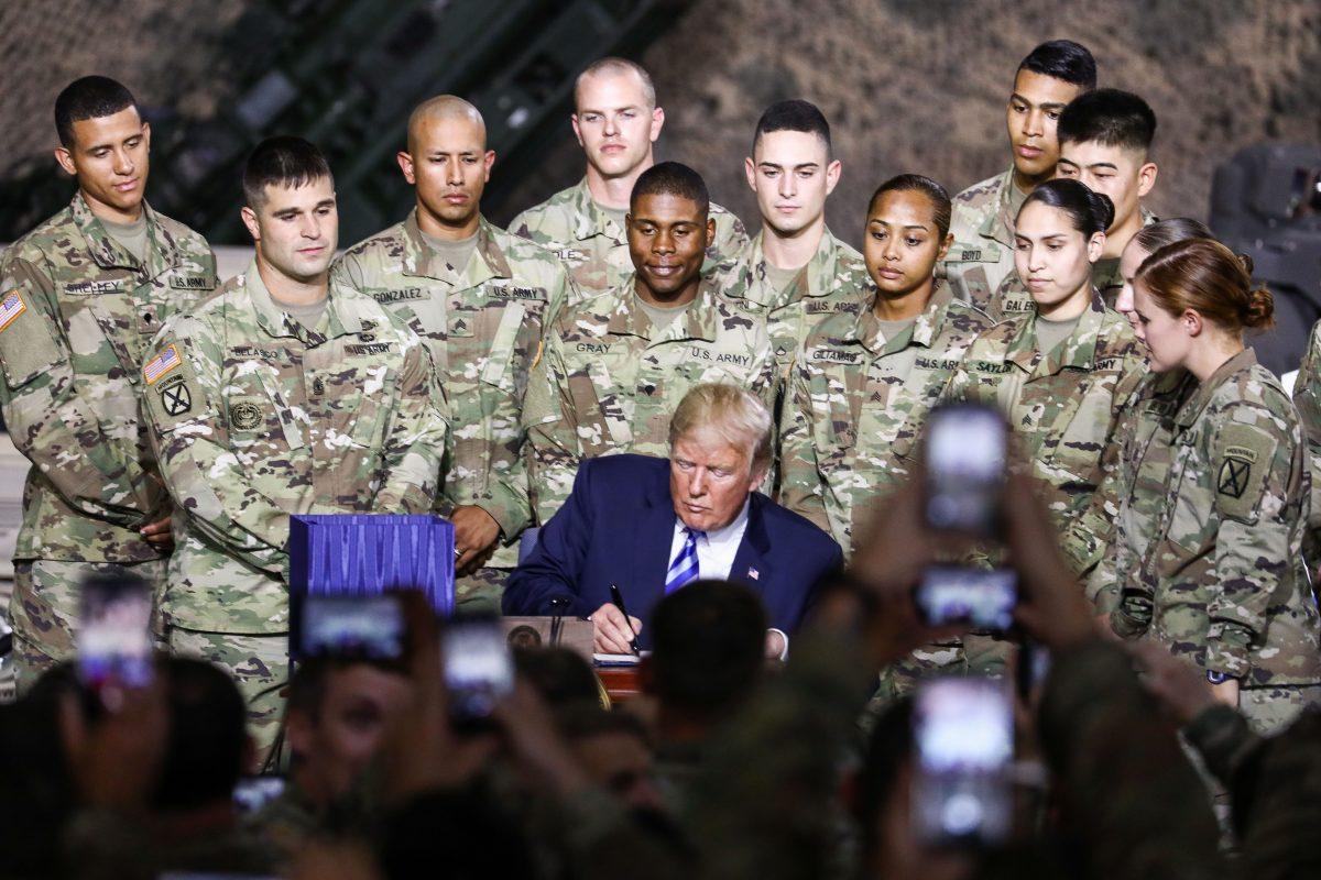 President Donald Trump signs the 2019 National Defense Authorization Act at Wheeler-Sack Army Airfield in Fort Drum, N.Y., on Aug. 13, 2018. (Charlotte Cuthbertson/The Epoch Times)
