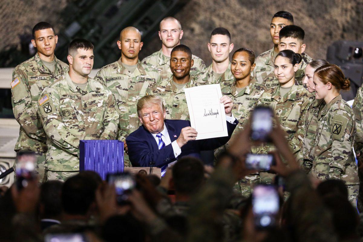 President Donald Trump signs the 2019 National Defense Authorization Act at Wheeler-Sack Army Airfield at Fort Drum, N.Y., on Aug. 13, 2018. (Charlotte Cuthbertson/The Epoch Times)