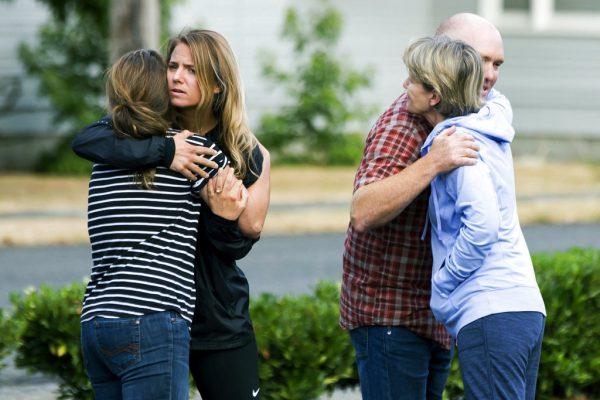 Friends of Richard Russell give parting hugs after making a statement to the media Saturday, Aug. 11, 2018, at the Orting Valley Police and Fire Department, in Orting, Wash. Russell is presumed dead after stealing a Horizon Airlines plane from SeaTac International Airport and crashing it into Ketron Island in the Puget Sound. (Bettina Hansen /The Seattle Times via AP)