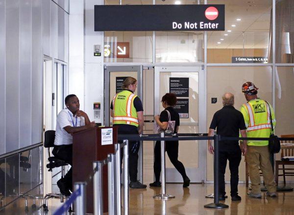 Workers at Seattle-Tacoma International Airport enter a secured area of the airport through a screening area Monday, Aug. 13, 2018, in SeaTac, Wash. A turboprop plane was stolen from the airport by an airline ground agent on Friday, and later crashed into a small island in the Puget Sound, killing the man. (AP Photo/Elaine Thompson)