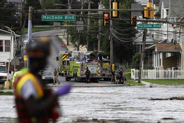 Firefighters look on as floodwaters rise over a road in Darby, Pa., Monday, Aug. 13, 2018. (AP Photo/Matt Rourke)