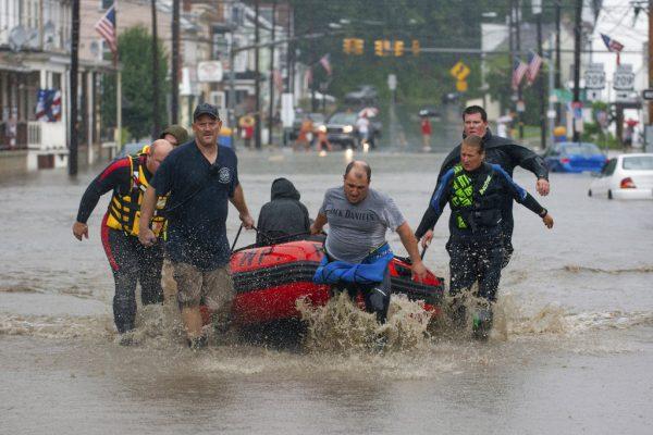 The Ryan Township dive team uses a boat to transport a person for medical problems along Pike Street in Port Carbon, Pa., on Monday, Aug. 13, 2018. (David McKeown/Republican-Herald/AP)