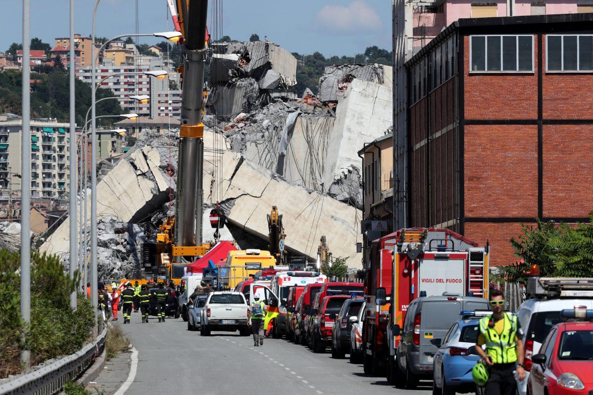 Firefighters and rescue workers stand at the site of a collapsed Morandi Bridge in the port city of Genoa, Italy, on Aug. 15, 2018. (Stefano Rellandini/Reuters)