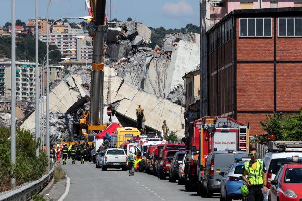 Firefighters and rescue workers stand at the site of a collapsed Morandi Bridge in the port city of Genoa, Italy, Aug. 15, 2018. (Stefano Rellandini/Reuters)