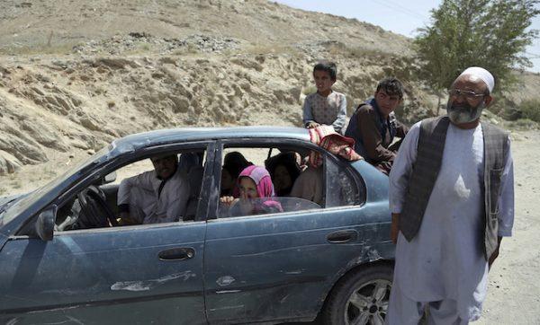 An Afghan family, who have escaped from the volatile city of Ghazni province, are seen at a checkpoint in Maidan Shar, west of Kabul, Afghanistan, on Aug. 13, 2018. (AP Photo/Rahmat Gul)