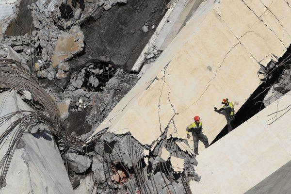 Italian rescuers climb onto the rubble of the collapsed Morandi motorway bridge searching for victims and survivors in the northern port city of Genoa on Aug. 14, 2018. (Valery Hache/AFP/Getty Images)