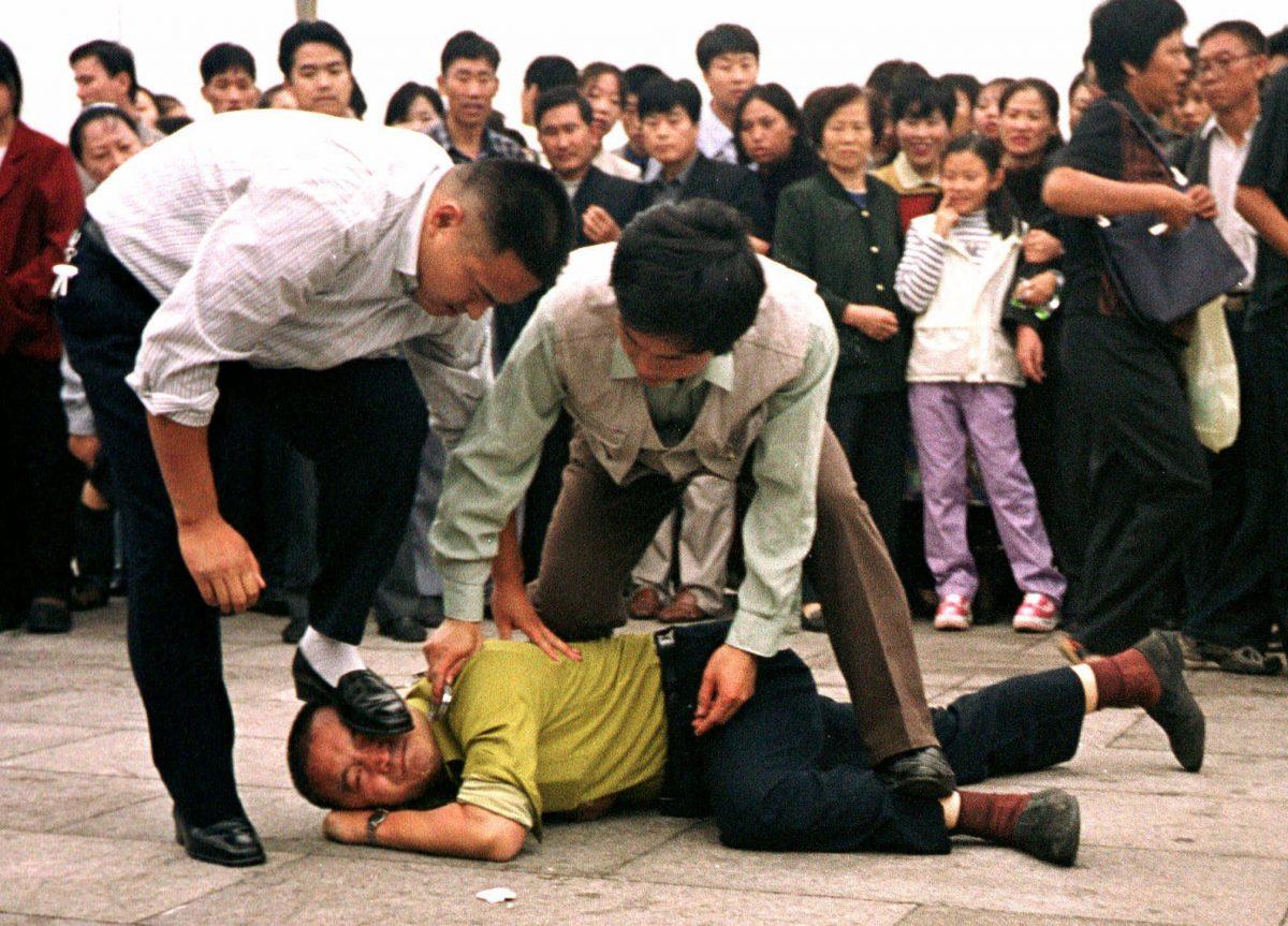 Police detain a Falun Gong protester in Tiananmen Square as a crowd watches in Beijing in this Oct. 1, 2000, photo. (AP Photo/Chien-min Chung)