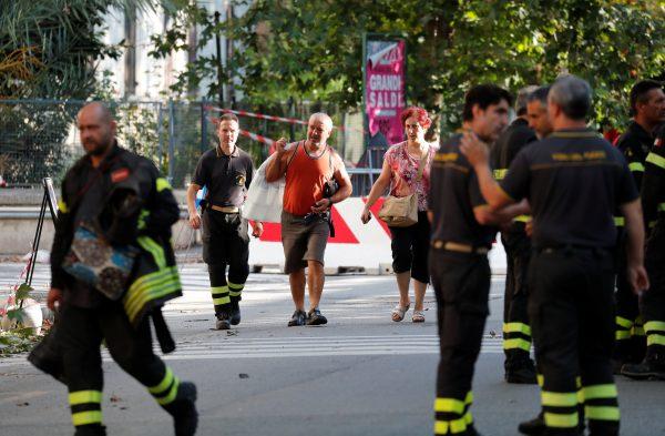Evacuees are escorted by firefighters after they recovered personal belongings from their homes following the Morandi Bridge collapse. (Stefano Rellandini/Reuters)