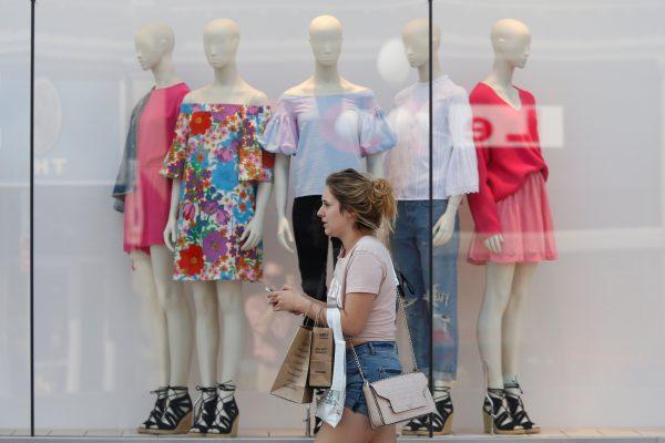 A woman carries shopping bags while walking past a window display outside a retail store in Ottawa, Ontario, Canada, July 21, 2017. (Reuters/Chris Wattie)