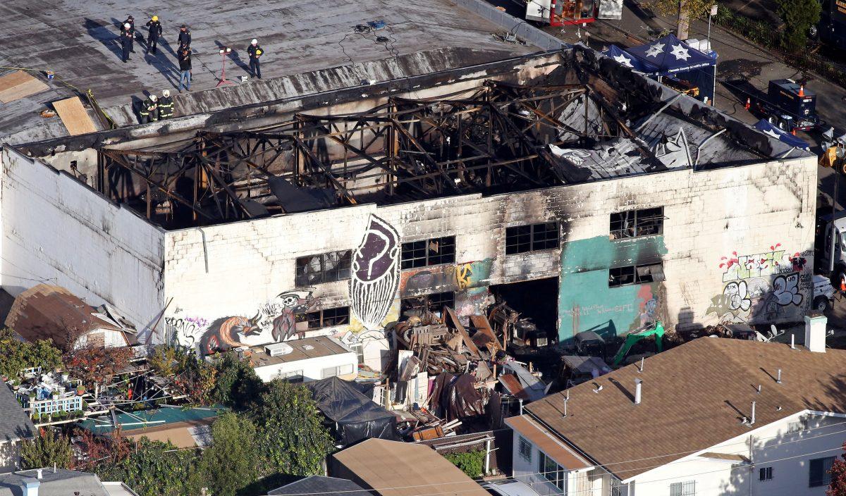 Recovery teams examine the charred remains of the two-story converted warehouse that caught fire killing dozens in Oakland, Calif., on Dec. 4, 2016. (Reuters/Lucy Nicholson)
