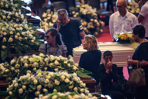 Relatives mourn by coffins of the victims of the Morandi Bridge disaster at the Fiera di Genova exhibition centre ahead of a state funeral service on August 18, 2018 in Genoa, Italy. (Jack Taylor/Getty Images)