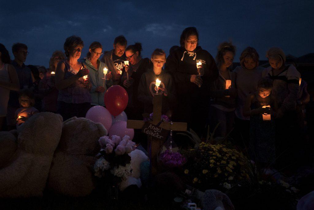 Mourners gather in front of a memorial for a candlelight vigil for Shanann Watts and her two daughters, Bella, 4, and Celeste, 3, in front of the Watts’s home on Friday, Aug. 17, 2018, in Frederick, Colo. Authorities are expected to file formal charges Monday against Christopher Watts, an oil and gas worker who authorities said dumped his wife and daughters' bodies on his employer's property. (Timothy Hurst/The Coloradoan via AP)