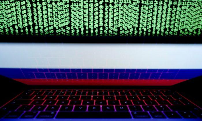A Russian flag is seen on a laptop screen in front of a computer screen displaying cyber code. (Reuters/Kacper Pempel)