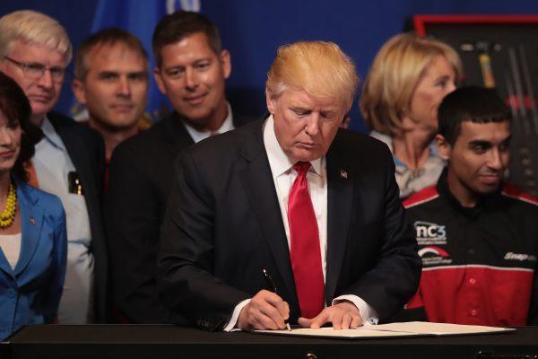 President Donald Trump signs an executive order to try to bring jobs back to American workers and revamp the H-1B visa guest worker program during a visit to the headquarters of tool manufacturer Snap-On in Kenosha, Wis., on April 18, 2017. (Scott Olson/Getty Images)