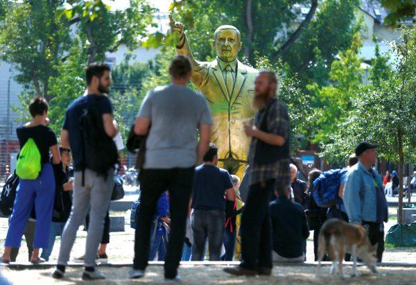 People mingle outside the venue of the "Wiesbaden Biennale" in Wiesbaden, Germany, with a golden statue of the president of Turkey in the background, on Aug. 28, 2018. (Reuters/Ralph Orlowski)