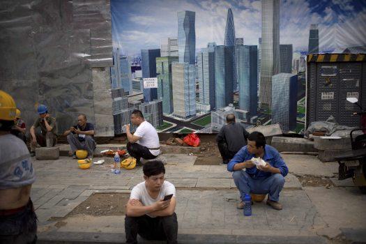 Construction workers take their lunch break at a construction site in Beijing on July 19. Overbuilding of infrastructure is one way the communist regime has boosted China’s economy. (AP Photo/Mark Schiefelbein)