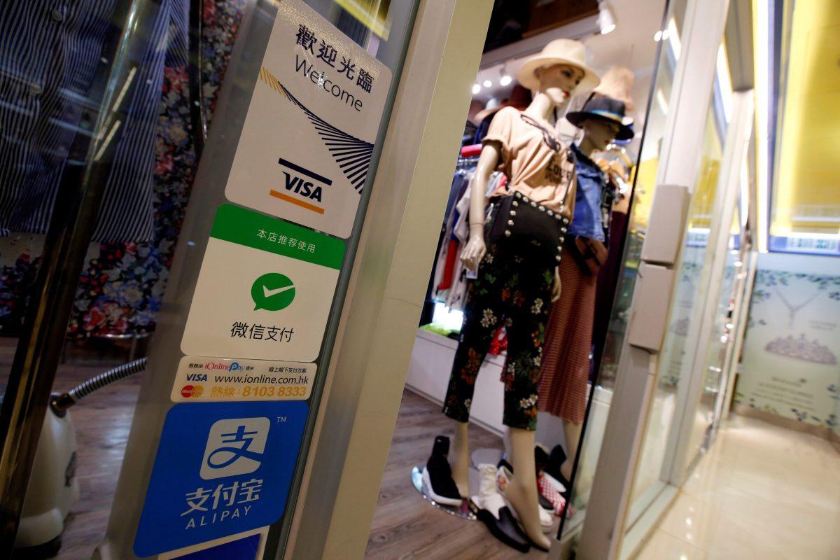 Labels of digital payment (from top) VISA, WeChat Pay, and Alipay are displayed outside a boutique at a shopping mall in Hong Kong, China, on July 31, 2018. (Reuters/Bobby Yip).