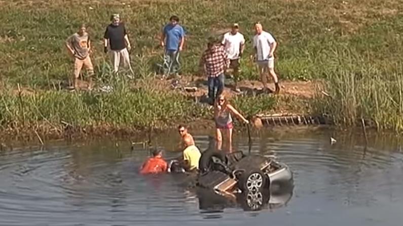 Three bystanders pull Joanna Girmscheid (head visible, middle) out of the water after her car flipped and slid into a retention pond in Huntley, Illinois, on August 3. (Illinois State Police via Storyful screenshot)
