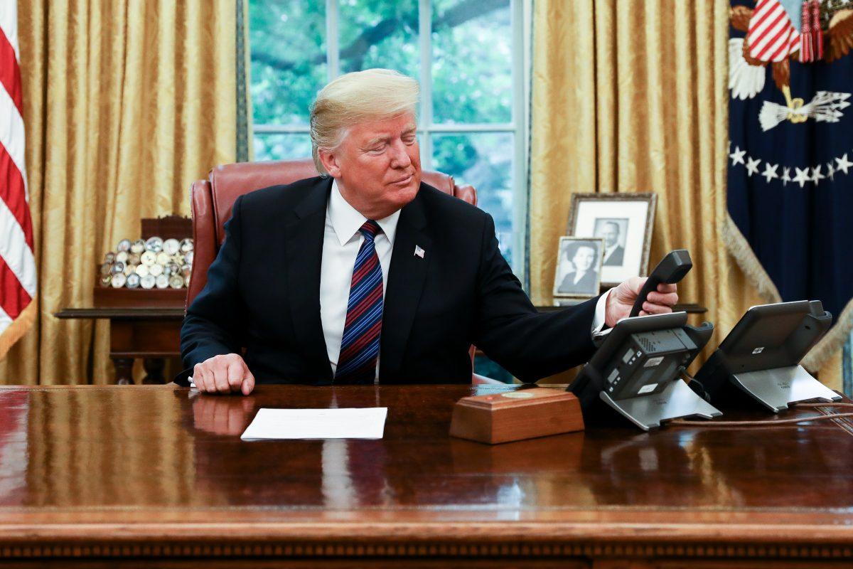 President Donald Trump hangs up the phone after speaking with President Pena Nieto of Mexico via a translator, in the Oval Office. (Samira Bouaou/The Epoch Times)