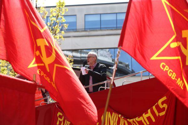 Britain's opposition Labour Party leader Jeremy Corbyn gives a speech from the top of a double-decker bus as Communist Party of Great Britain (Marxist-Leninist) flags fly at a May Day rally in London on May 1, 2016. (Justin Tallis/AFP/Getty Images)
