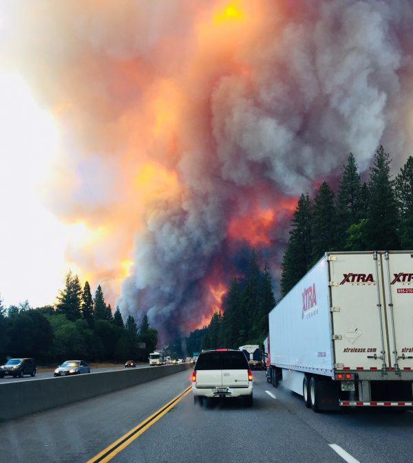 A fire rages as motorists travel on Interstate 5 near Lake Shasta, California, Wednesday, Sept. 5, 2018. (Jerri Tubbs via AP)