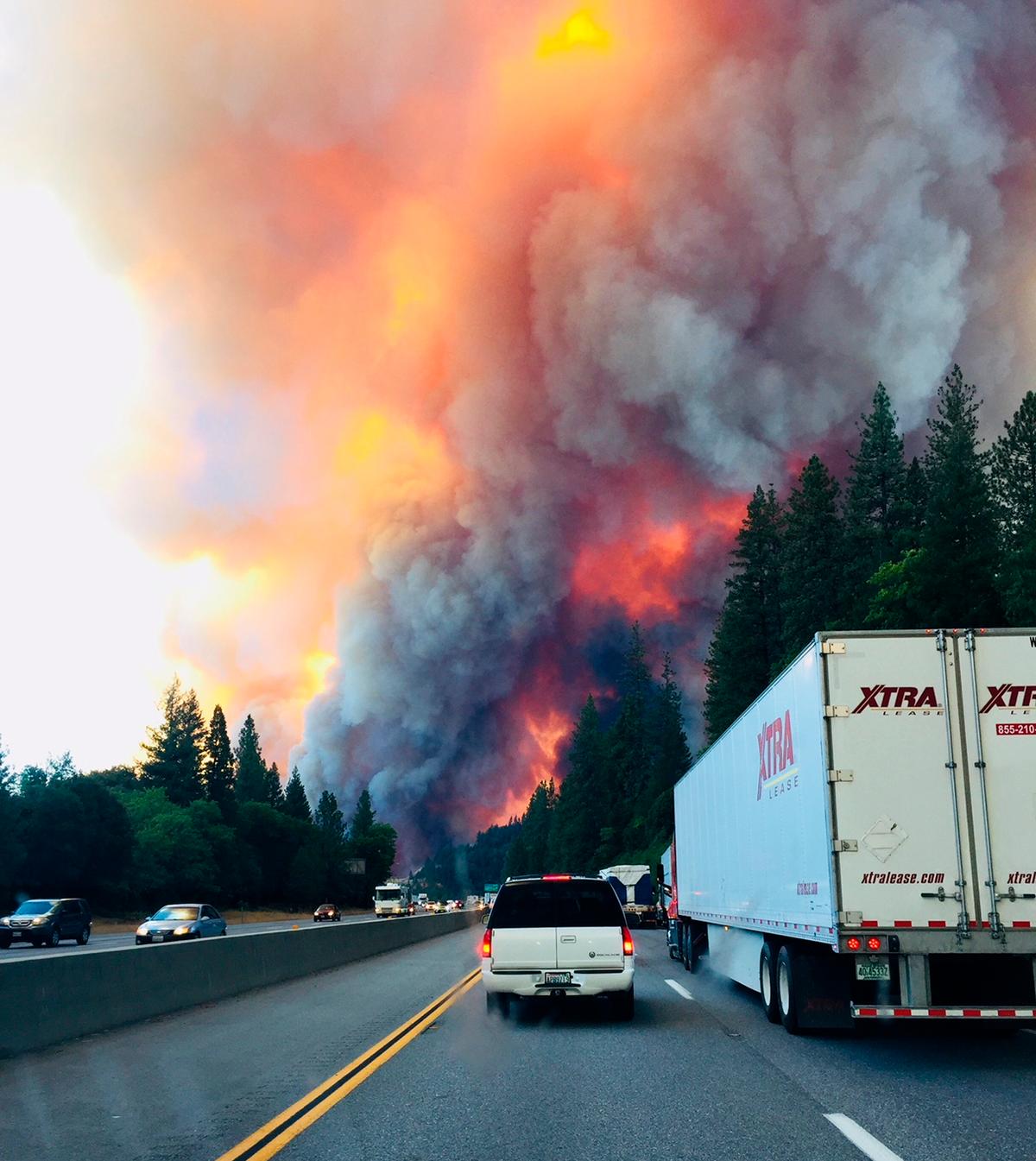 A fire rages as motorists travel on Interstate 5 near Lake Shasta, California, Wednesday, Sept. 5, 2018. (Jerri Tubbs via AP)