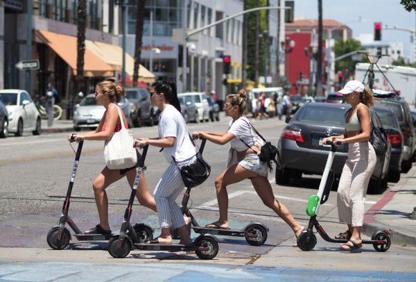 Young women ride shared electric scooters in Santa Monica, Calif. on July 13, 2018. (Robyn Beck/AFP/Getty Images)