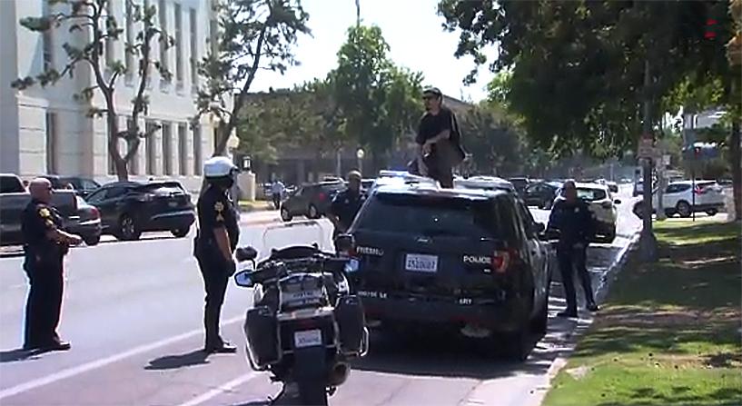 Adolfo Martinez Lopez climbed on top of a parked Fresno Police Department cruiser for some unknown reason, and refused to come down. (CNN screenshot)