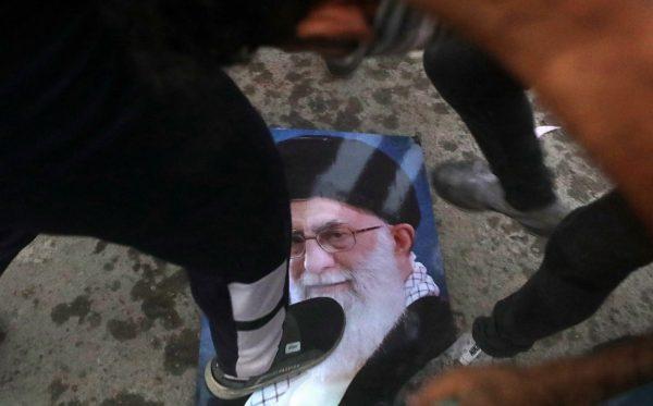 Protesters trample a portrait of Iran's supreme Leader Ayatollah Ali Khamenei, during the storming and burning the Iranian consulate in Basra, 340 miles (550 km) southeast of Baghdad, Iraq, Friday, Sept. 7, 2018. (AP Photo/Nabil al-Jurani)
