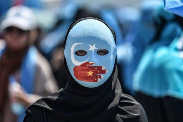 A demonstrator wearing a mask painted with the colours of the flag of East Turkestan and a hand bearing the colours of the Chinese flag attends a protest of supporters of the mostly Muslim Uighur minority and Turkish nationalists to denounce China's treatment of ethnic Uighur Muslims, in front of the Chinese consulate in Istanbul on July 5, 2018. (Ozan Kose/AFP/Getty Images)