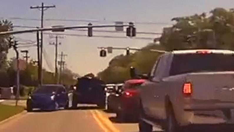 The fleeing black vehicle barely squeezes between oncoming car and the car it is passing as it roars through an intersection at full speed. (Screenshot/NTD)