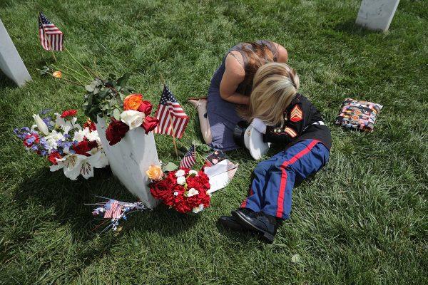 Brittany Jacobs of Hertford, North Carolina, embraces her son while sitting next to the grave of her husband, U.S. Marine Corps Sgt. Chris Jacobs, at Arlington National Cemetery on Memorial Day May 29, 2017 in Arlington, Virginia. (Chip Somodevilla/Getty Images)