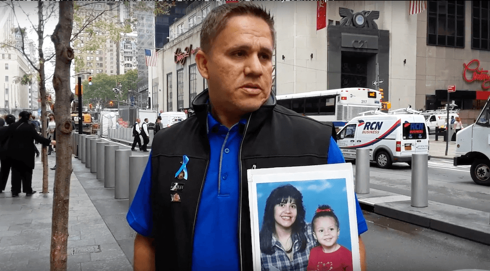 Hiram Gonzalez carries a photo of his late sister Nereida DeJesus with her daughter Lauren the Ground Zero memorial service on Sept. 11, 2018. (The Epoch Times)