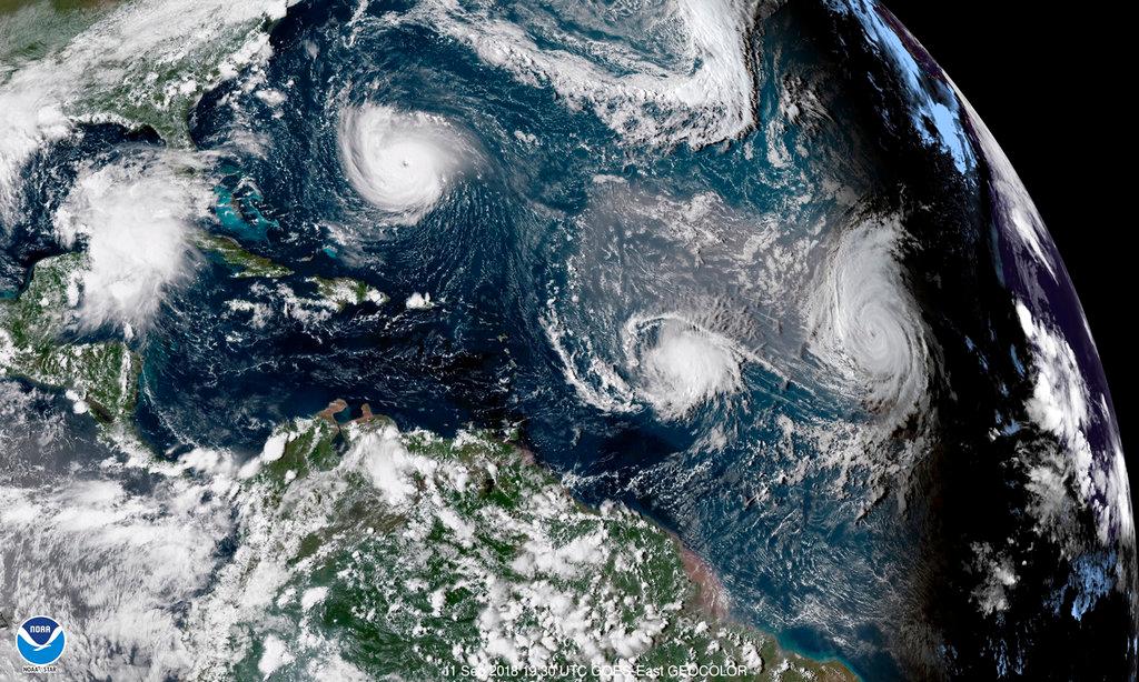 An enhanced satellite image shows Tropical Storm Florence, upper left, in the Atlantic Ocean. At center is Tropical Storm Isaac and at right is Hurricane Helene. The image is from Sept. 11, 2018. (NOAA via AP)