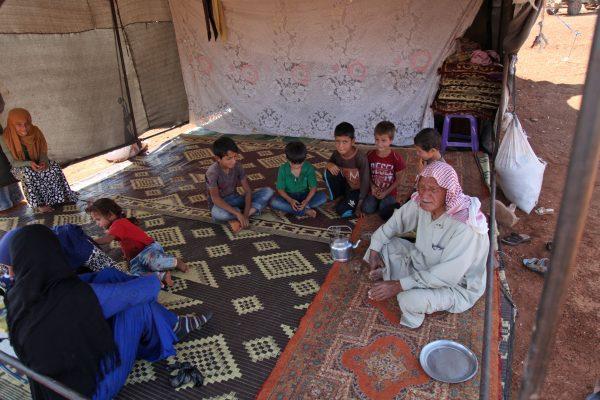 A Syrian family gathers in a tent at a camp for displaced civilians fleeing from advancing Syrian government forces on Sept. 5, 2018. (Photo by Amer Alhamwe/AFP/Getty Images)