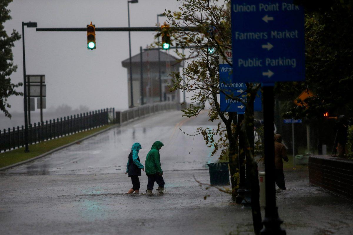 People walk on a local street as water from Neuse River starts flooding houses upon Hurricane Florence coming ashore in New Bern, North Carolina, Sept. 13, 2018. (Reuters/Eduardo Munoz)