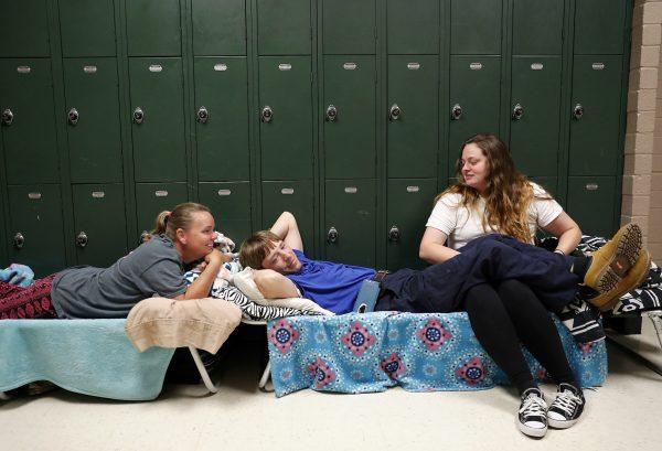 Vickie Grate, left, waits in a shelter with her son Chris, center, and his girlfriend Sarah for Hurricane Florence to pass after evacuating from their nearby homes, in Conway, South Carolina on Sept. 12, 2018. (AP Photo/David Goldman)