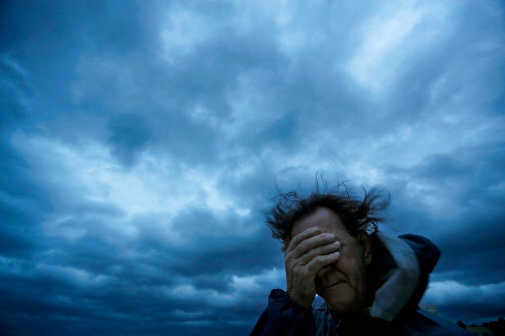 Russ Lewis covers his eyes from a gust of wind and a blast of sand as Hurricane Florence approaches Myrtle Beach, S.C., on Sept. 14, 2018. (AP Photo/David Goldman)