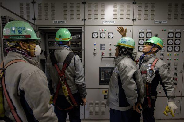 South Korean workers stand before instrument panels in the engine control room of an under-construction container ship at the Daewoo DSME shipyard in Okpo, south of Busan, on Dec. 3, 2014. (Ed Jones/AFP/Getty Images)